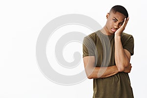 Guy hates long queues. Bored and indifferent attractive young african american male making face palm, leaning head on photo
