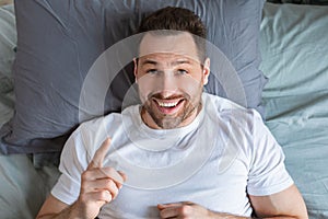 Guy Having Idea Pointing Finger Up Lying In Bed, Top-View