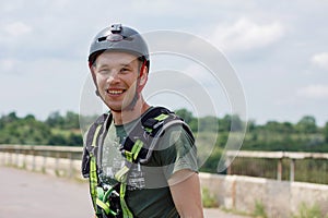 A guy in the helmet and special equipment is very happy and smiles after rope jumping from the bridge