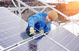 Guy with help of tools installs solar panels, snowy weather