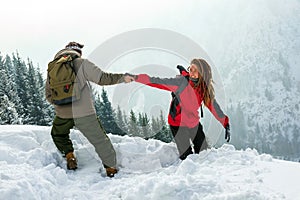 Guy helps the girl get out of the deep snow. winter trip.