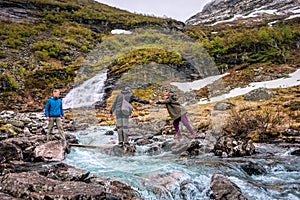 The guy helps the girl to cross the river