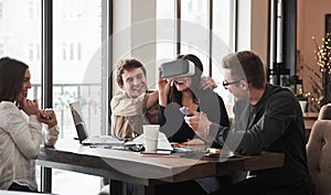 Guy helps girl to wear the virtual glasses Having fun in the office room. Friendly coworkers playing around at their
