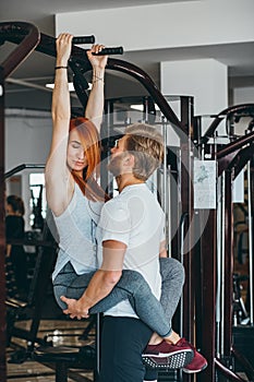 Guy hepl girlfriend on training in gym