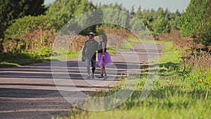 A guy and his girlfriend are on a country road. The frame on the long focus. Very beautiful couple in love.
