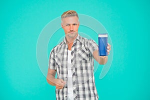 Guy hold bottle of mens bodywash blue background copy space, bodycare