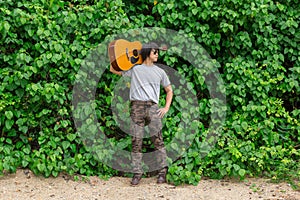 The guy is holding the guitar, outdoo, cargo pants