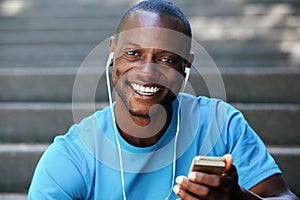 Guy holding mobile phone listening to music on headphones