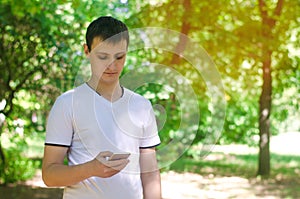 The guy is holding a mobile smartphone in park and looking at the screen. telephone dependence, social networks. work on the Inter