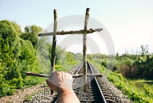 Guy is holding prisons grate made from wooden sticks. Freedom concept photo with rail tracks in the green field. Railway transport