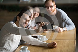 Guy holding smartphone making selfie with friends