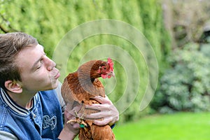 The guy holds the chicken in his hands and tries to kiss her