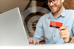 A guy holds credit card and using laptop