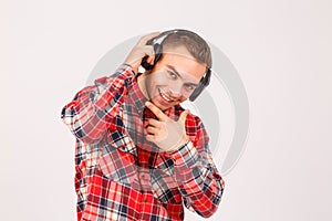 The guy holds his hand over the headphones and his hand at the chin on a gray background