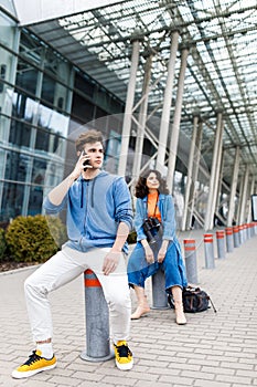 The guy holds the phone in his hands. Young cute couple - a boy and a girl travel around the city with binoculars in their hands.