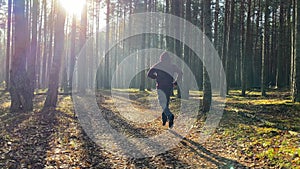 A guy in a hoodie runs through the autumn forest, wearing a hood on his head, exhaling steam into the frosty air.