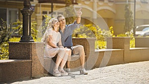 Guy hugging girlfriend on date, showing something in air, young couple in love