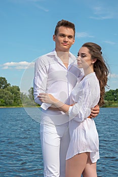 Guy hugs a girl near the water.