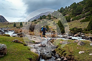 A guy jogs across a mountain river
