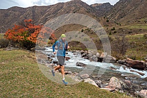 A guy jogs across a mountain river