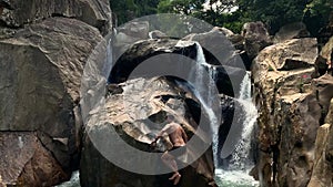 Guy jumping from rocky cliff on waterfall in Vietnam