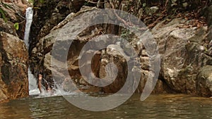 Guy Jumps Gambols in River Close to Waterfall Cascade