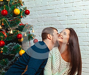 Guy kisses a girl under the tree on Christmas