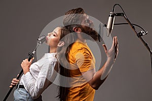 Guy and lady with excited faces enjoy music. Karaoke singer couple. Man and woman singing with music microphone.