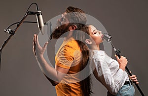 Guy and lady with excited faces enjoy music. Karaoke singer couple. Man and woman singing with music microphone.