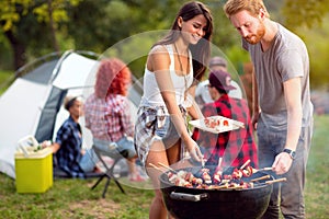 Guy and lassie putting grilled skewers on plate