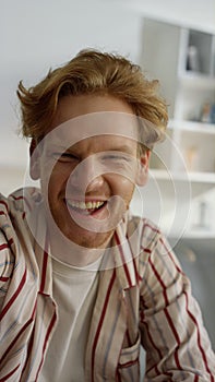 Guy laughing webcam call at home interior closeup. Joyful ginger man talk online