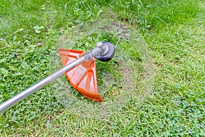 Guy with lawn mower in front of back yard.Close up of young worker with a string lawn trimmer mower cutting grass in