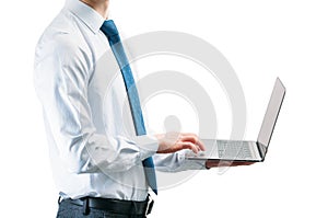 A guy in a light shirt with a tie on a white background is typing on a laptop keyboard.