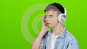 Guy listens to the music in the headphones and adjusts to the positive. Green screen