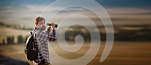 Guy looking at binoculars in hill. man in t-shirt with backpack