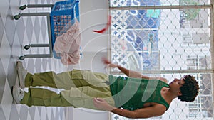 Guy looking laundry basket in service vertical. Frustrated man holding red sock