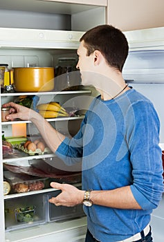 Guy looking for something in pan near fridge