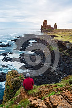 Guy looks at the rocks of Londrangar in Iceland photo
