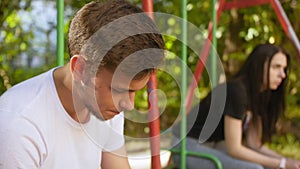 The guy looks towards the sad girl and hold out her hand in summer on the playground. Close up shot.