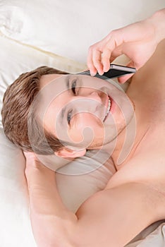 Guy lying in bed and speaking on mobile phone