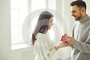 The guy makes a marriage proposal to the girl. Smiling man gives a marriage proposal ring of in the room.