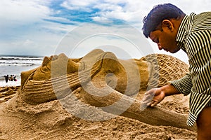 A guy making a mermaid sand statue in sandy seabeach art