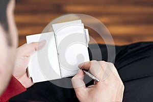 Guy making notes on a small diary while sitting relaxed in a wooden floored room