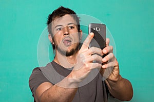 Guy making a selfie with funny faces. Guy taking pictures with his smartphone