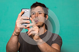 Guy making a selfie with funny faces. Guy taking pictures with his smartphone