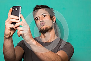 Guy making a selfie with funny faces. Guy taking pictures with his smartphone