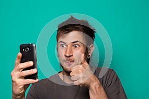 Guy making a selfie with funny faces. Guy taking pictures with his smartphone