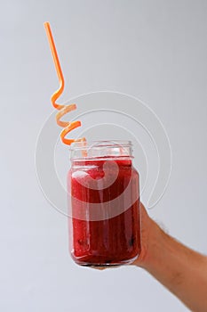 Guy, a man holding mason jar mug with a fruit, berry smoothie in his hand, a colored tube, the concept of raw food, healthy