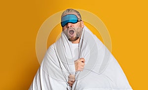 Guy in mask for sleep yawns in blanket