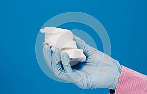 A guy in a medical glove holds cotton pads. Blue background. Medical and cosmetology content